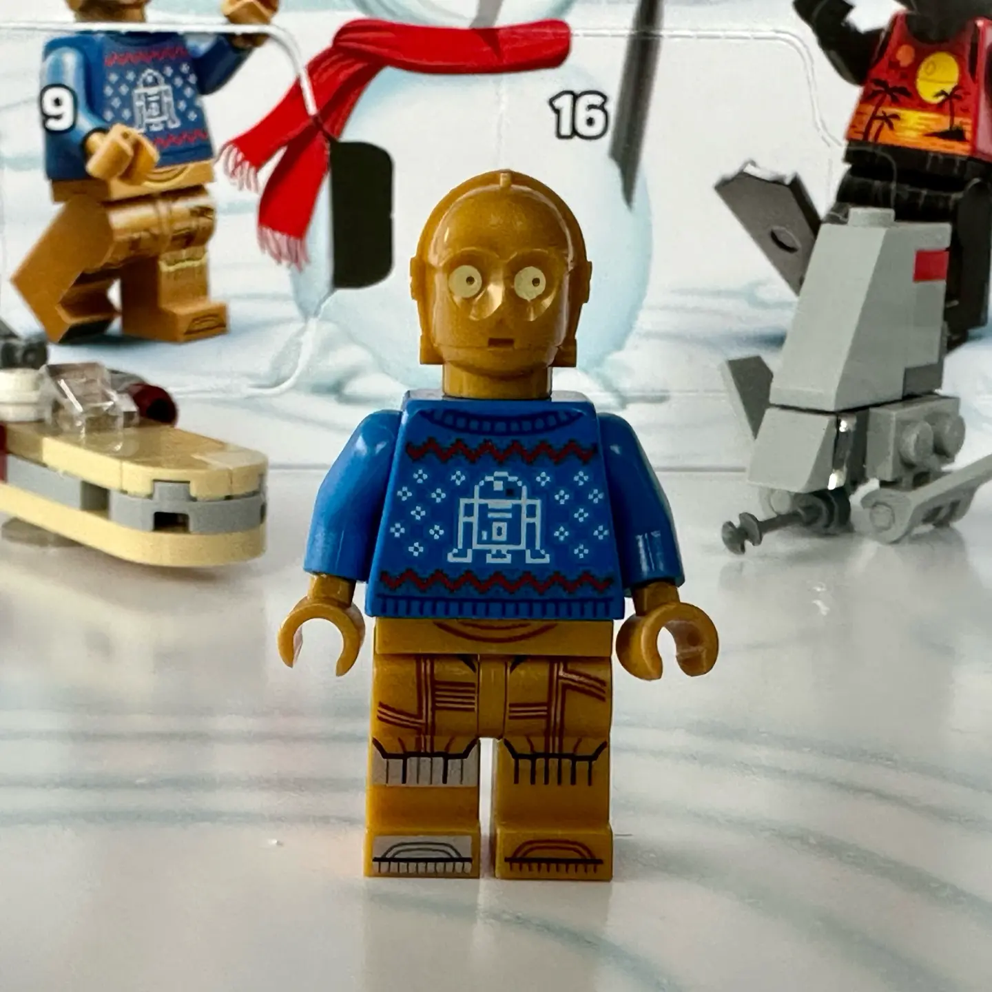 LEGO minifigure C-3PO wearing a blue knitted holiday sweater with R2-D2 pattern