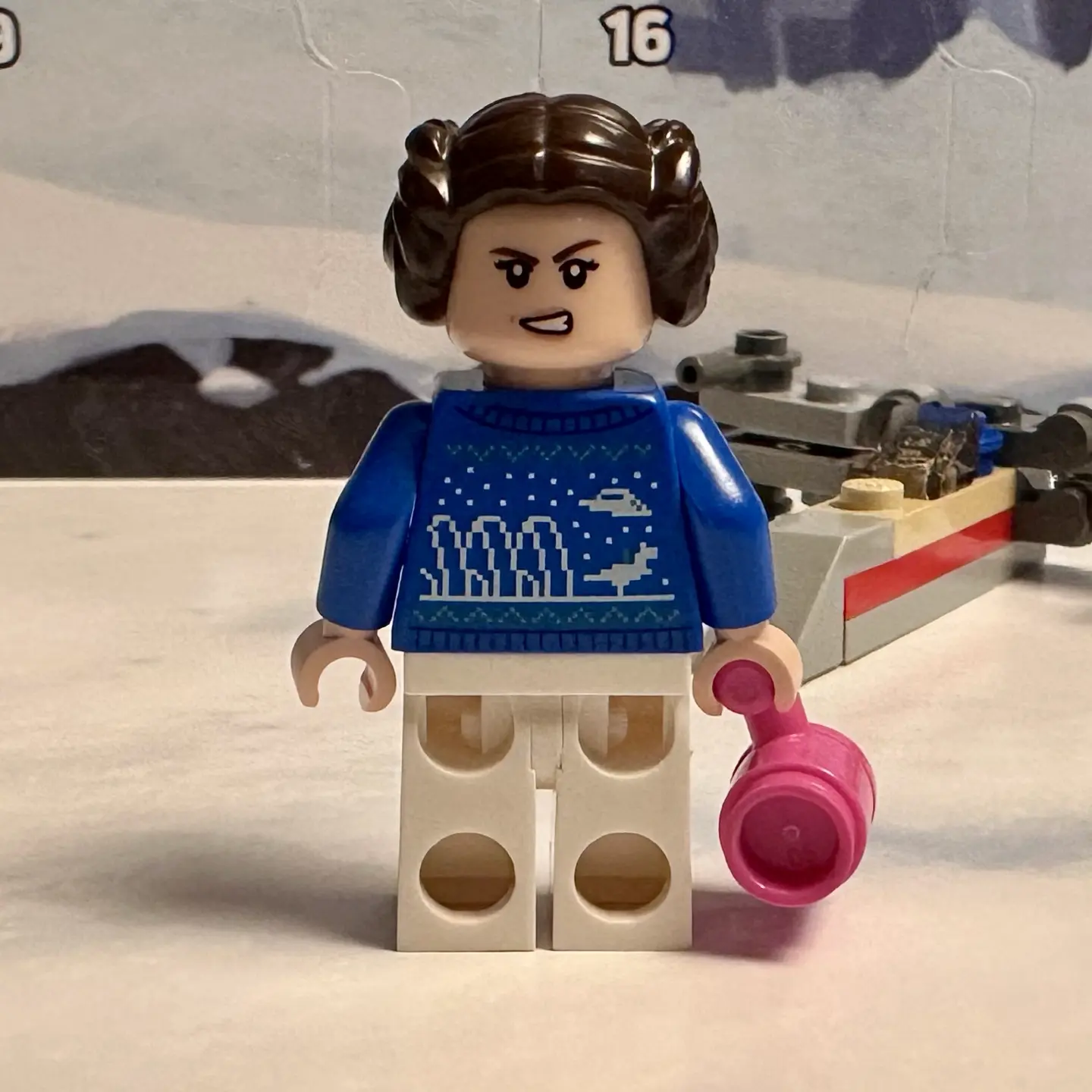 Back side of holiday sweater Leia Organa minifigure. Her blue knitted sweater is decorated with shield generators, a snowspeeder, and a tauntaun with rider.