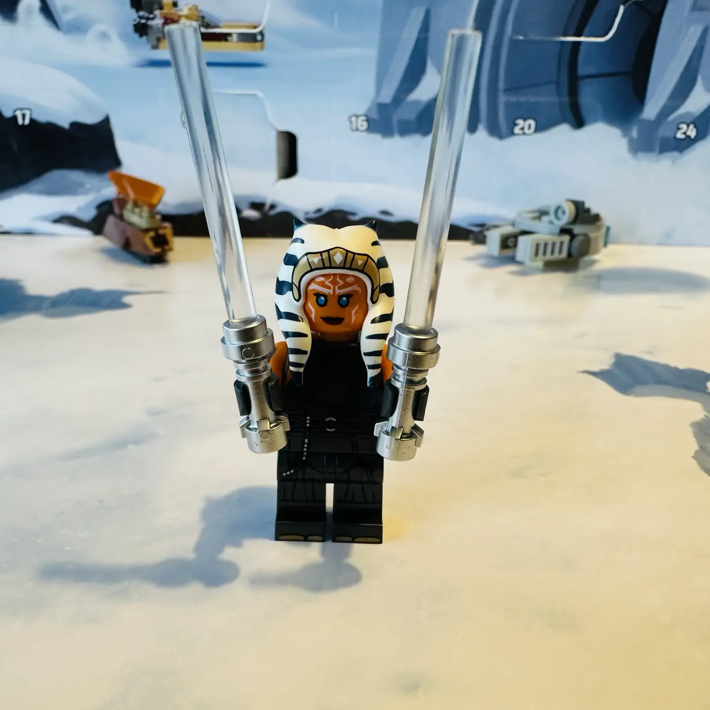 LEGO minifigure of Ahsoka Tano wielding two light sabers with metallic silver hilts and colorless blades