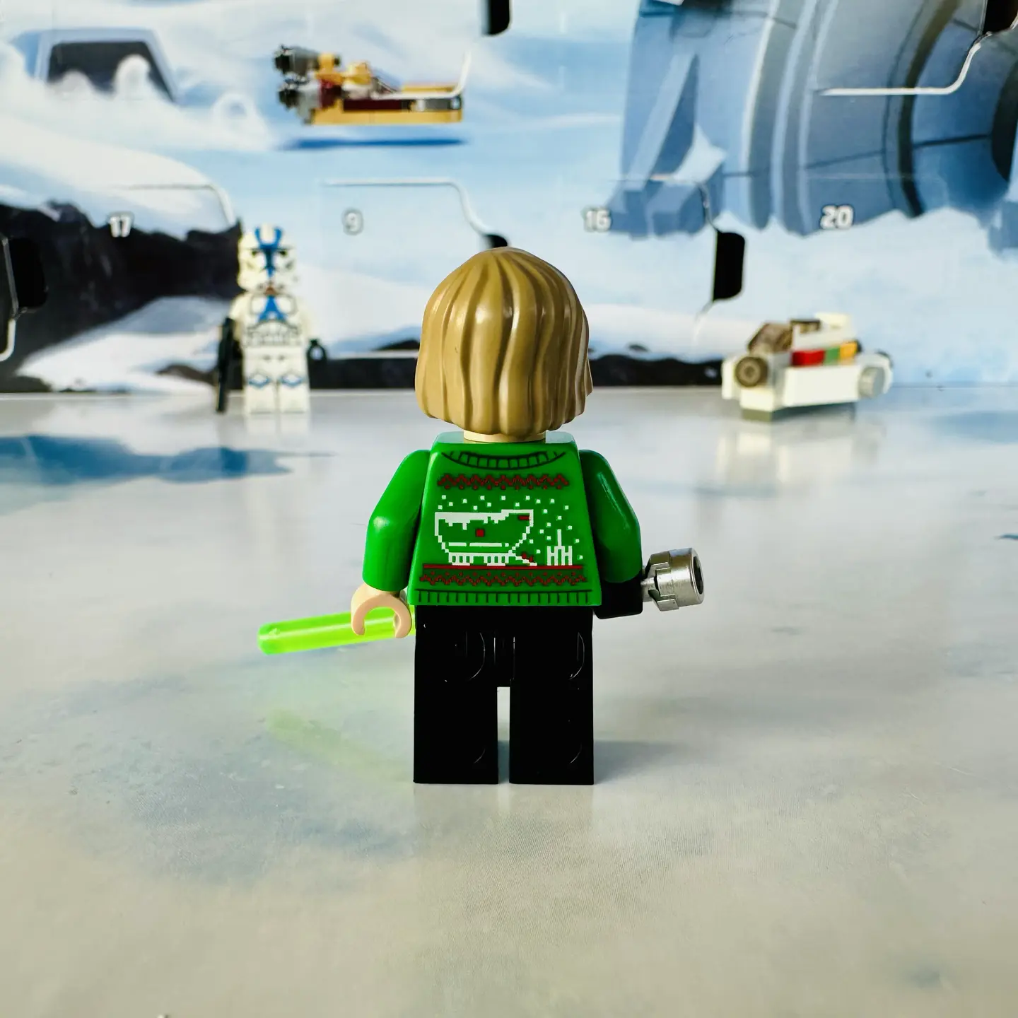 Back side of holiday sweater Luke Skywalker minifigure. His green knitted sweater is decorated with a Jawa Sandcrawler and another moisture vaporator.