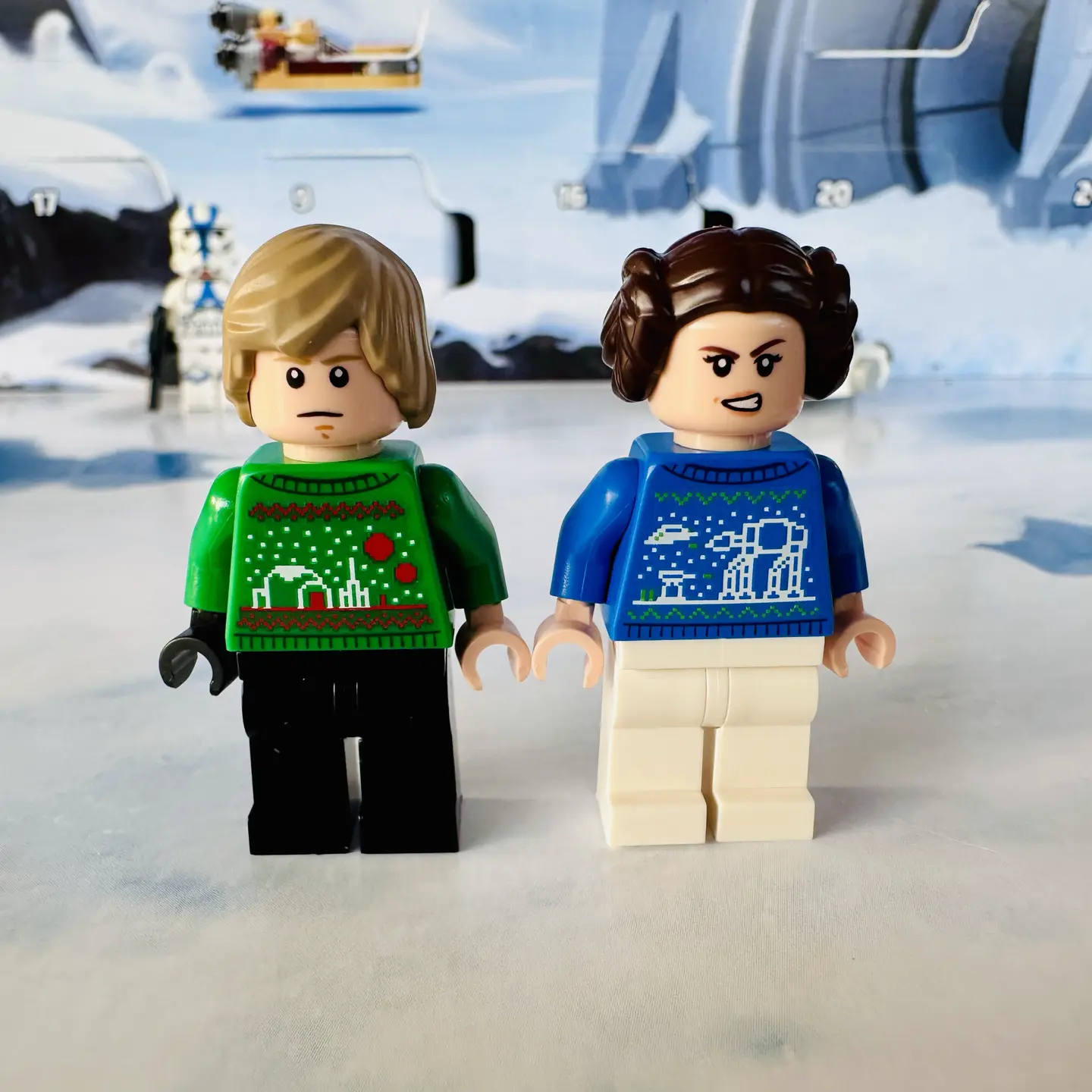 Holiday sweater Luke Skywalker LEGO minifig stands next to holiday sweater Leia minfig.