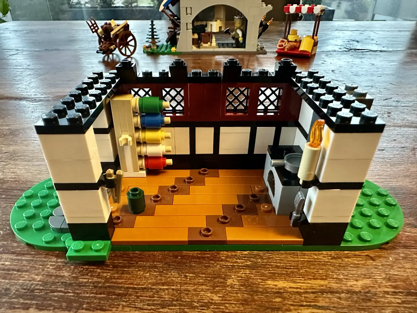 LEGO ground floor of a farmhouse built in the Tudor half-timbered style. The interior features a hearth and a rack holding five spools of yarn.