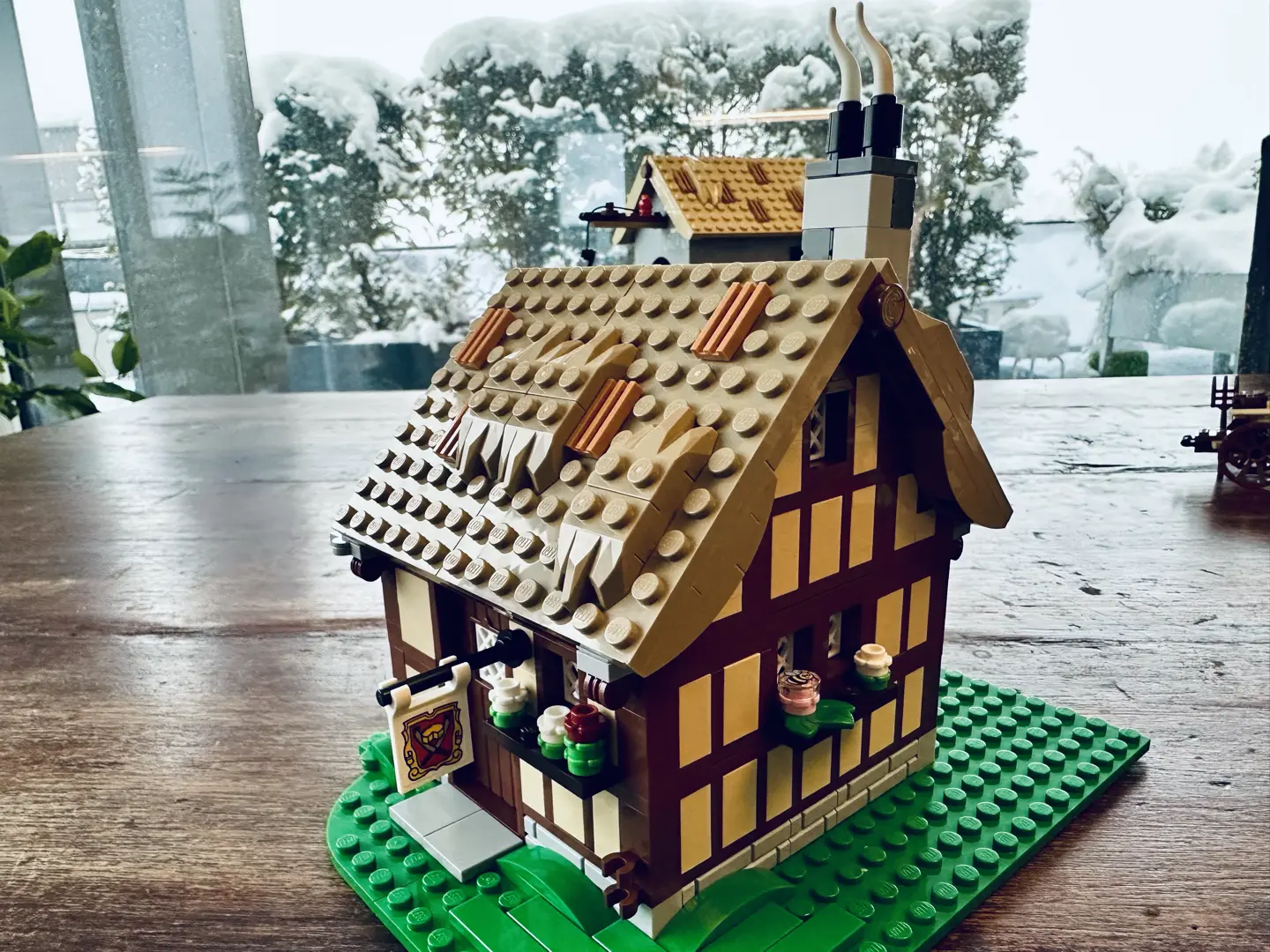 LEGO cheese maker's shop with light tan and brown half-timbered walls and tan thatched roof with smoking chimney