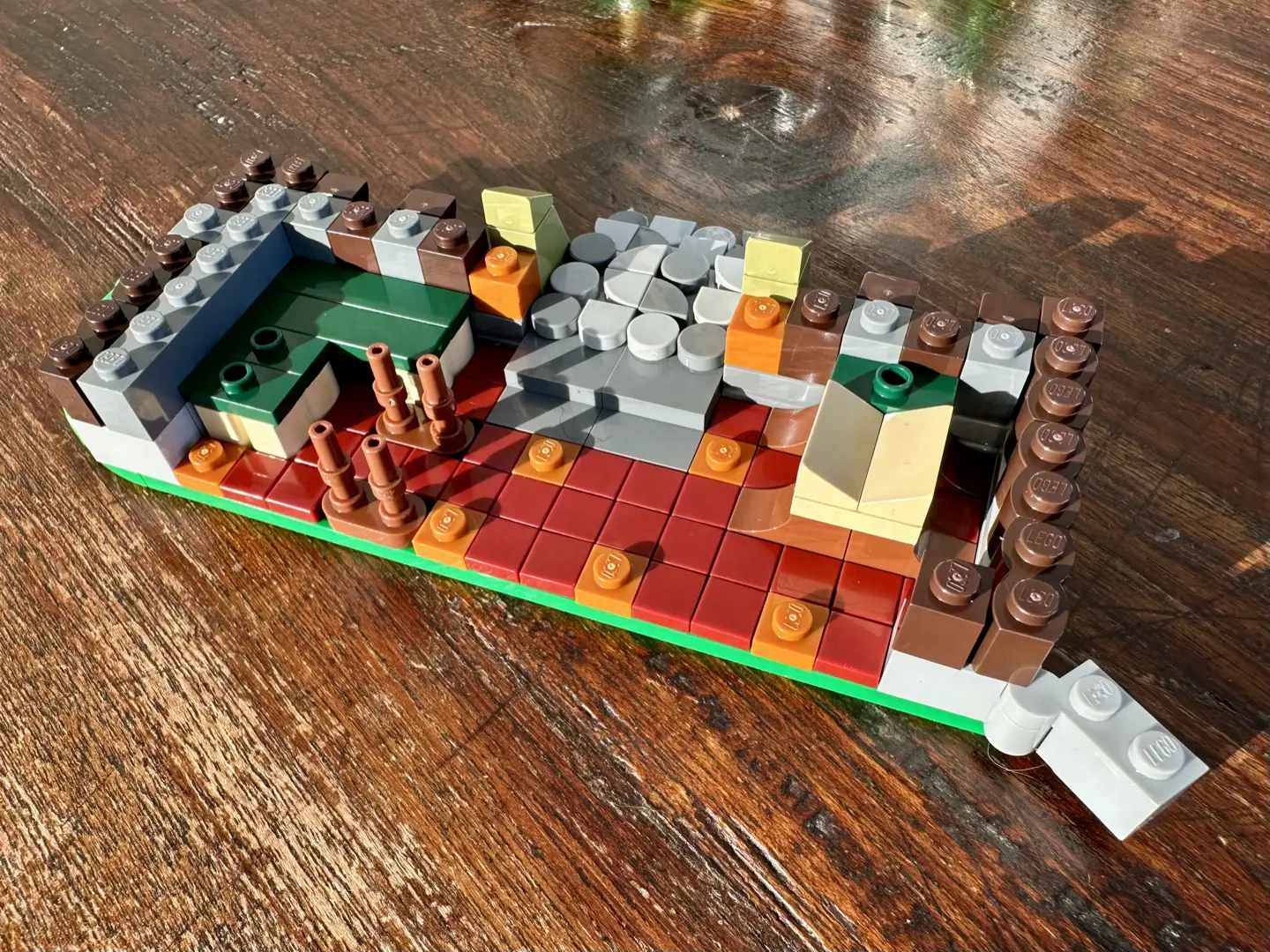 Foundations of a LEGO tavern. The walls are gray stone and brown wood. Cobbled stone steps form an entryway, and the floor is tiled in dark red and orange.