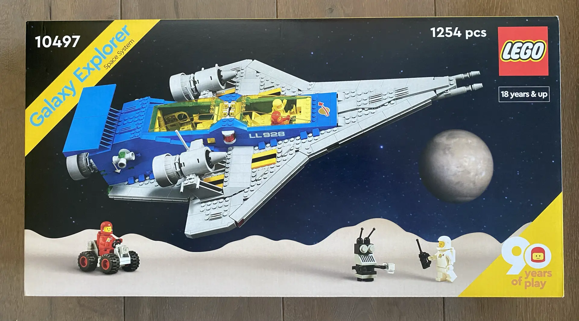 Front of box for LEGO set 10497 Galaxy Explorer showing a gray and blue spaceship flying above a planet surface with two astronauts and a robot