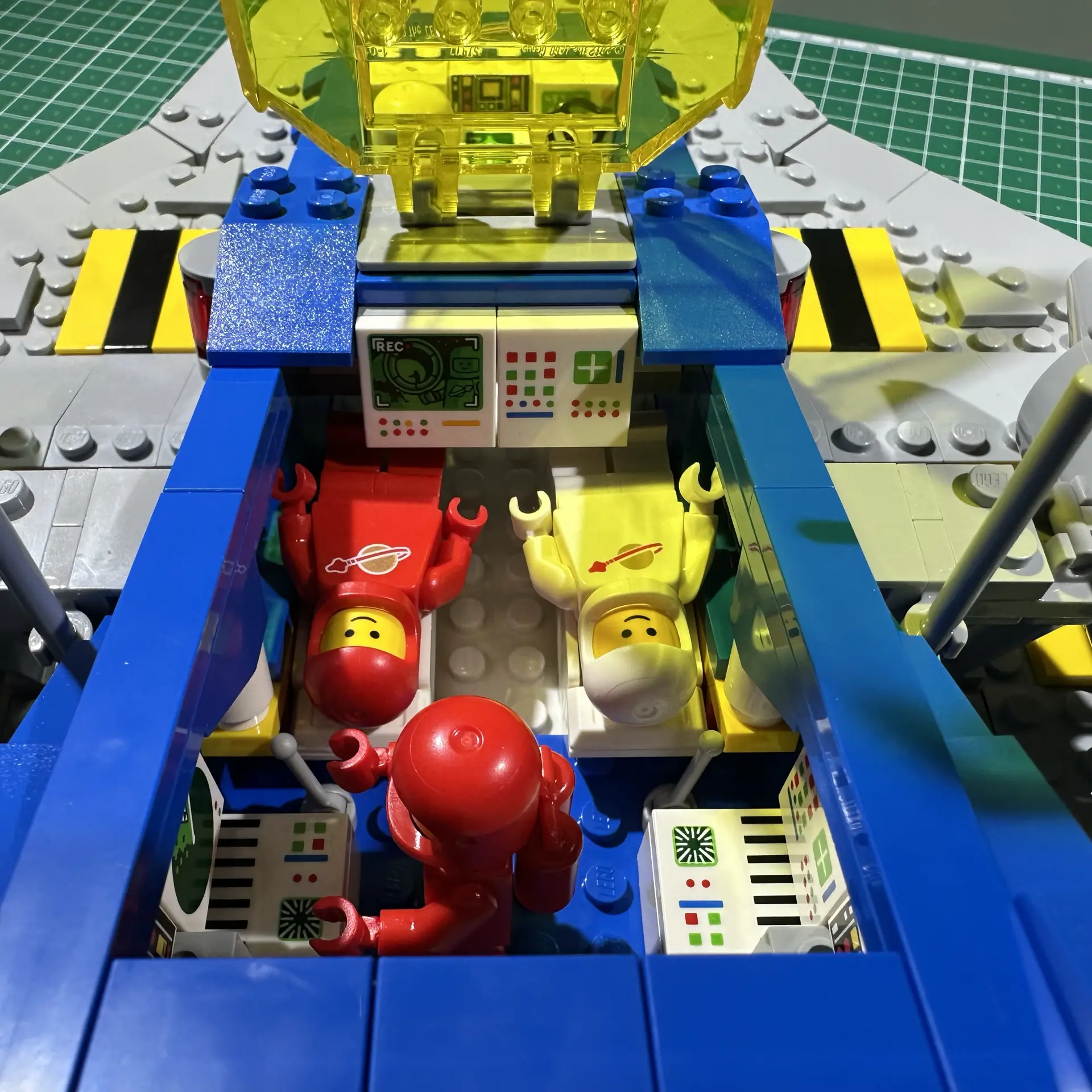 Closeup of the midsection of the Galaxy Explorer with two astronauts lying in beds and a third standing before a computer terminal