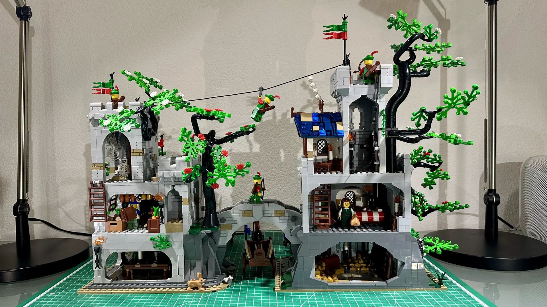 Back side of LEGO set 910043 built on my desk. It consists of two gray stone castles joined by an arched bridge. The back side is open and displays the interiors of the various rooms. Each tower consists of three floors.